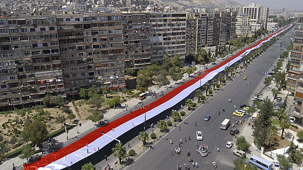 Thousands of supporters of Syrian President Bashar Assad carry a 2,300-metre-long Syrian flag in a demonstration in  Damascus on Wednesday. The Syrian government is working to stop the spectacle of Syrians fleeing in terror from government troops trying to quell the three-month rebellion.  Muzaffar Salman/Associated Press