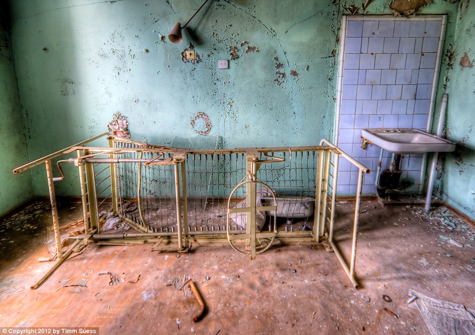 An overturned bed frame lies rusty with what appears to be a broken lamp overhead and small basin to the right. Workers started on a project to build a giant structure that will cover the exploded nuclear reactor at the power station