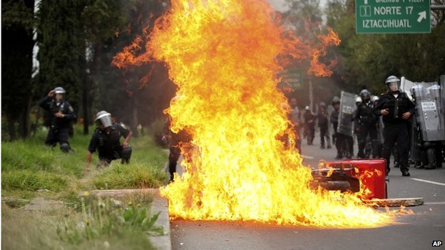 A motorcycle burns after protesters threw molotov cocktails at riot police near the airport in Mexico Cityon 20 November 2014. 